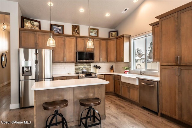 kitchen featuring a breakfast bar, sink, a center island, hanging light fixtures, and stainless steel appliances