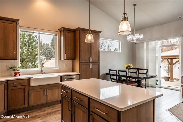 kitchen featuring hanging light fixtures, a healthy amount of sunlight, sink, and decorative backsplash