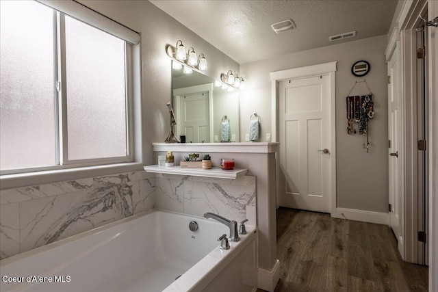 bathroom with a bathtub, wood-type flooring, and a textured ceiling