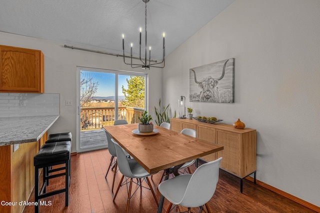 dining room featuring lofted ceiling, wood-type flooring, and a notable chandelier