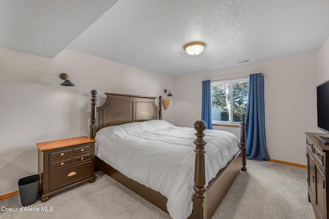 bedroom with light colored carpet and a textured ceiling