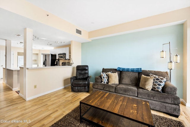 living room with rail lighting and light hardwood / wood-style flooring