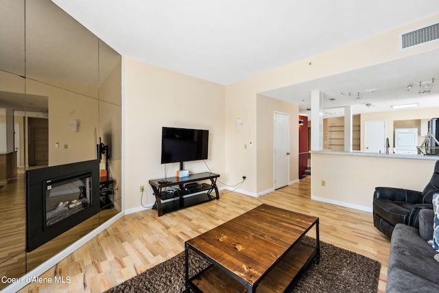 living room featuring rail lighting and light hardwood / wood-style floors