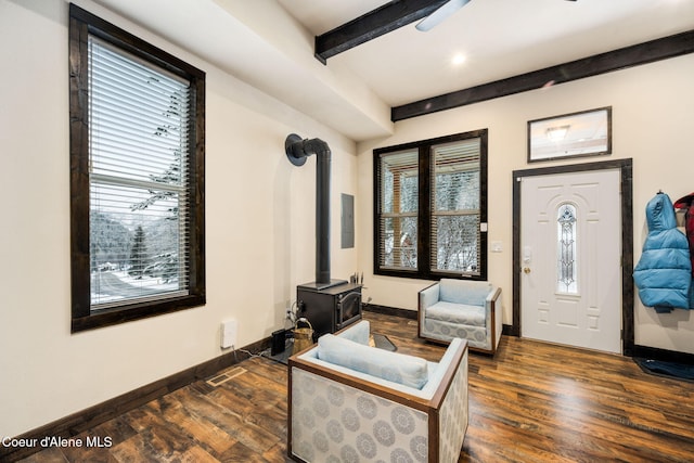 sitting room with beamed ceiling, a wood stove, and dark hardwood / wood-style flooring