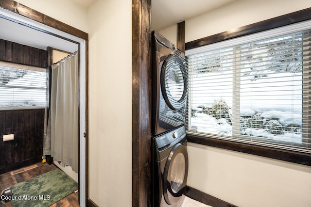 laundry area with hardwood / wood-style flooring and stacked washer / dryer