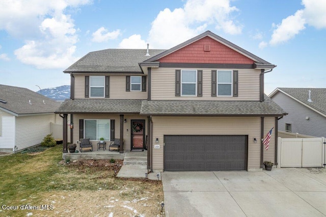 view of front of home featuring a porch, a garage, a mountain view, and a front yard