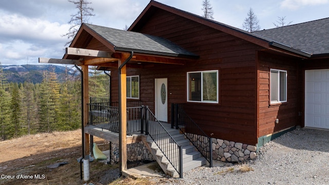 rustic home with gravel driveway, a garage, and a shingled roof