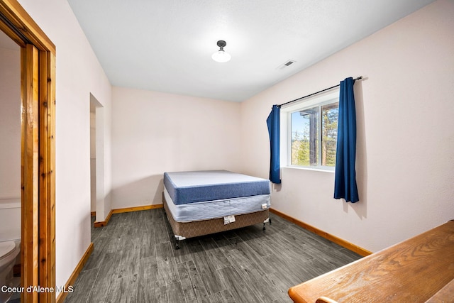 bedroom with visible vents, baseboards, and wood finished floors