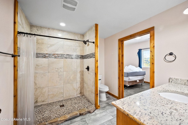 bathroom with visible vents, tiled shower, toilet, and vanity