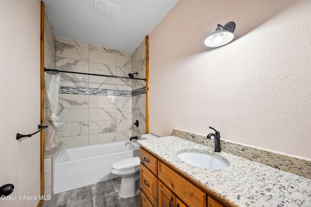 bathroom featuring tub / shower combination, toilet, vanity, and a textured wall