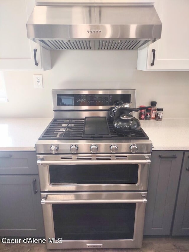 kitchen featuring ventilation hood, double oven range, gray cabinetry, and white cabinetry