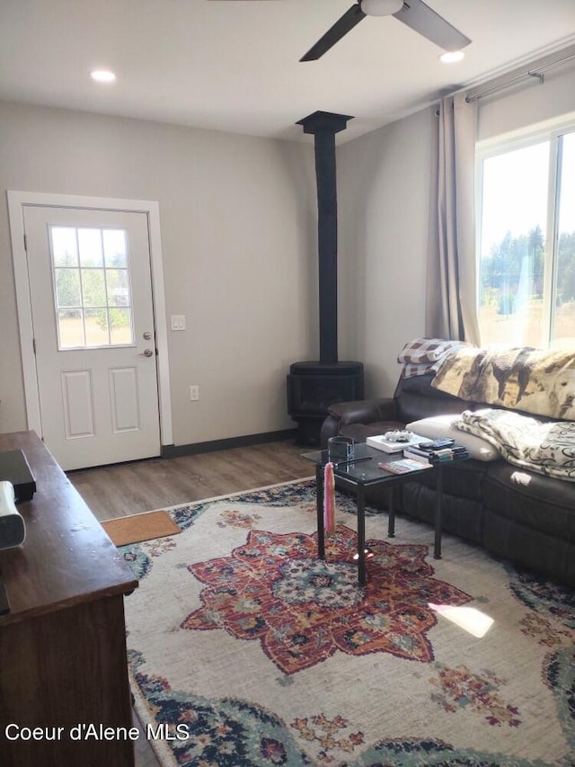 living room featuring ceiling fan, a wood stove, and light wood-type flooring