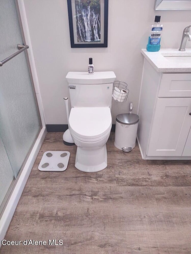 bathroom featuring walk in shower, vanity, toilet, and wood-type flooring