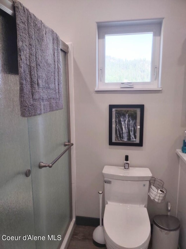 bathroom with a shower with shower door and toilet