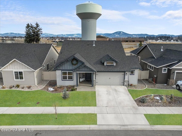 view of front of property with a garage, a mountain view, and a front lawn