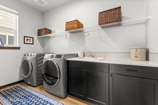 washroom featuring cabinets, independent washer and dryer, sink, and light wood-type flooring