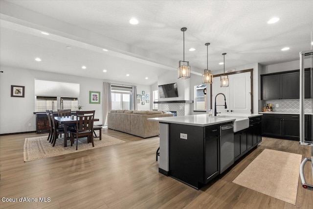 kitchen with dishwasher, a kitchen island with sink, and light hardwood / wood-style flooring