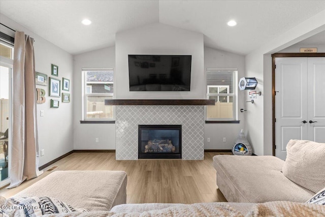 living room featuring a tile fireplace, lofted ceiling, and light hardwood / wood-style floors