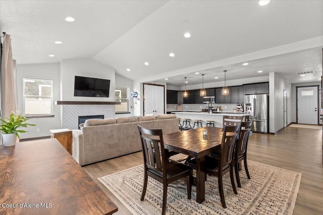 dining room with vaulted ceiling, a tile fireplace, and dark hardwood / wood-style floors