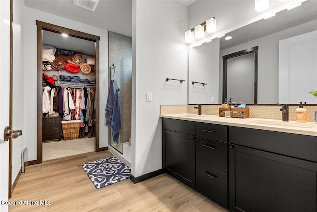 bathroom featuring tasteful backsplash, vanity, hardwood / wood-style floors, and walk in shower