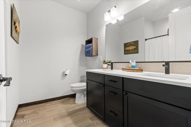 bathroom featuring vanity, toilet, hardwood / wood-style floors, and backsplash