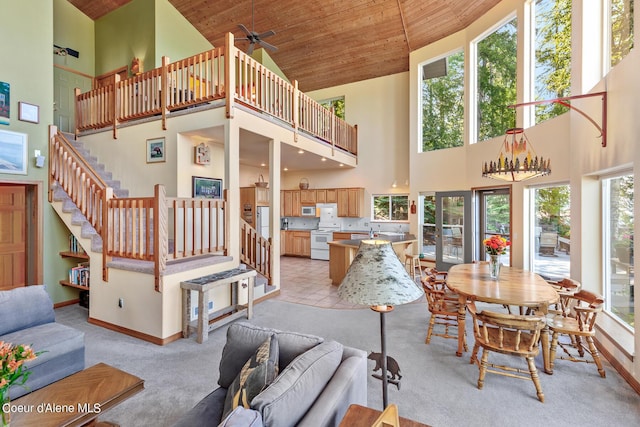 interior space with a towering ceiling, wooden ceiling, light colored carpet, and ceiling fan