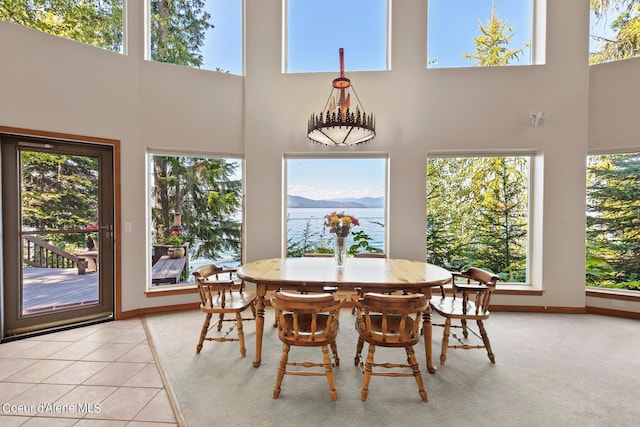 tiled dining space with a water view and a towering ceiling