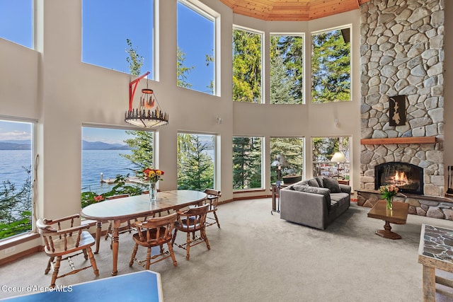 sunroom with a water view, a healthy amount of sunlight, wood ceiling, and a stone fireplace