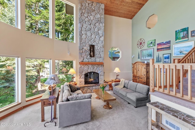 carpeted living room with high vaulted ceiling, a stone fireplace, and wooden ceiling