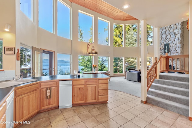 kitchen featuring sink, dishwasher, hanging light fixtures, a high ceiling, and light colored carpet