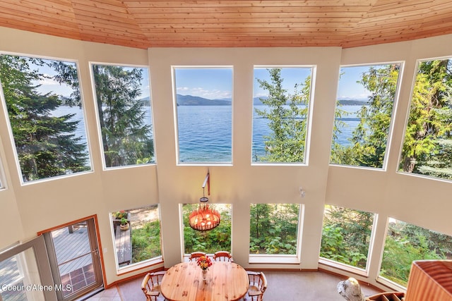 sunroom / solarium with a water view, plenty of natural light, an inviting chandelier, and wooden ceiling