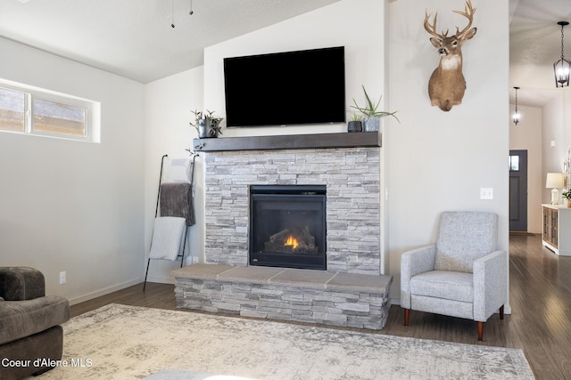 living room with a stone fireplace, dark wood-type flooring, and lofted ceiling