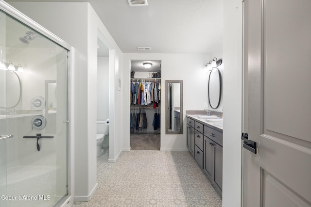 bathroom with a shower with door, vanity, and toilet