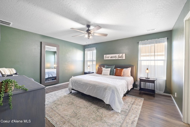 bedroom featuring ceiling fan, dark hardwood / wood-style floors, and a textured ceiling