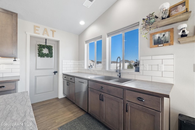 kitchen featuring lofted ceiling, sink, tasteful backsplash, stainless steel dishwasher, and light wood-type flooring