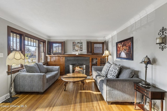 living room featuring crown molding, a brick fireplace, and hardwood / wood-style flooring