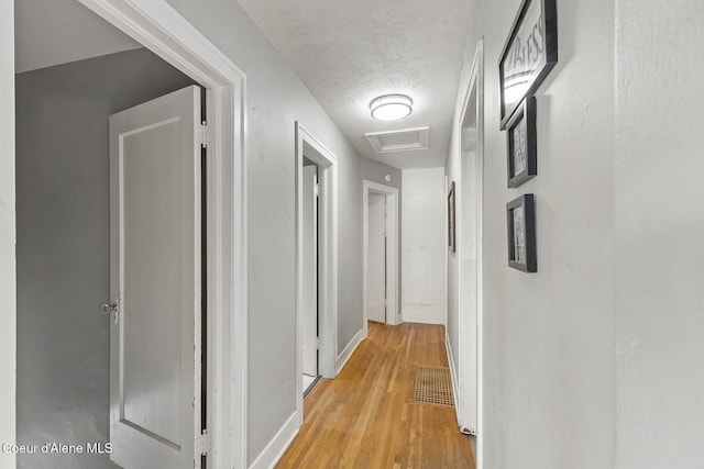 hall with light hardwood / wood-style floors and a textured ceiling