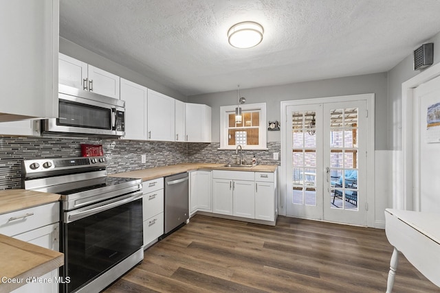 kitchen with decorative light fixtures, sink, white cabinets, stainless steel appliances, and french doors