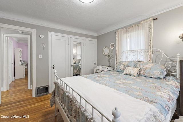 bedroom with hardwood / wood-style floors, crown molding, and a textured ceiling