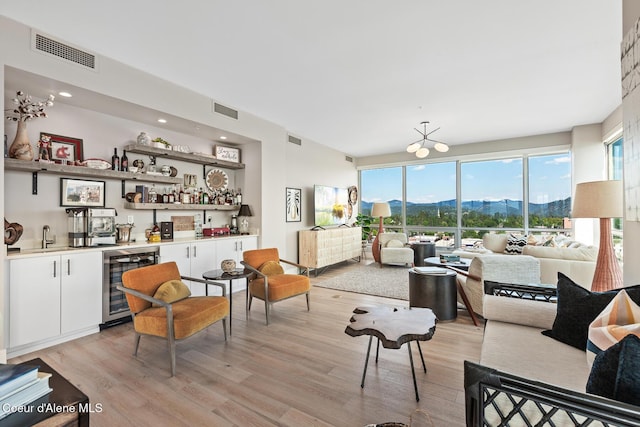 living room with wine cooler, light wood-type flooring, and indoor bar