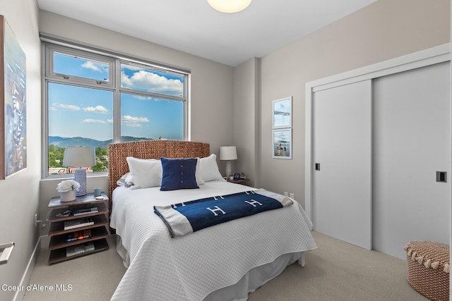 bedroom featuring a mountain view, light colored carpet, and a closet