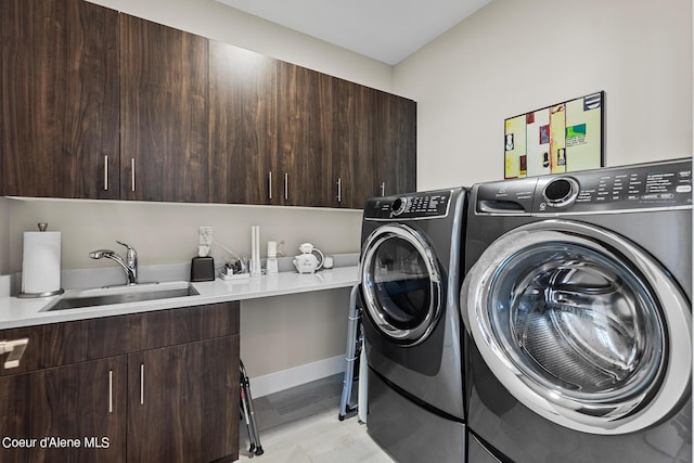 clothes washing area featuring sink, washer and clothes dryer, and cabinets