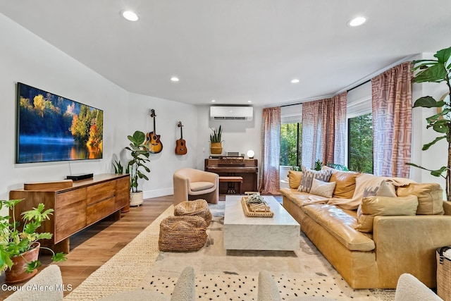 living room with a wall mounted AC and light hardwood / wood-style flooring