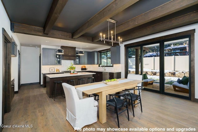 dining area featuring dark wood-type flooring, sink, and beam ceiling