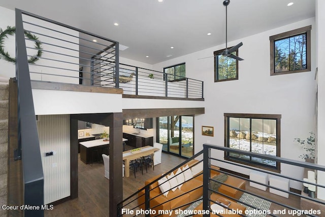 stairway featuring wood-type flooring, ceiling fan, and a high ceiling