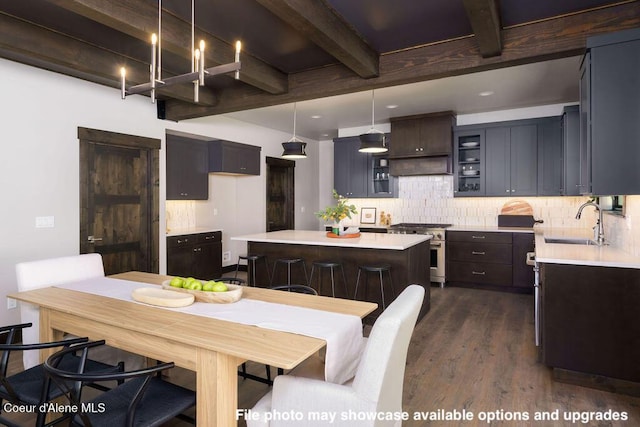 kitchen with sink, beamed ceiling, decorative light fixtures, a kitchen island, and high end stainless steel range oven