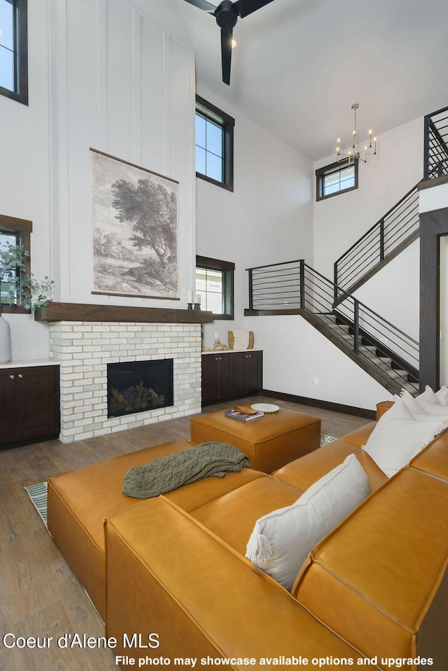 living room featuring a high ceiling, a brick fireplace, and hardwood / wood-style floors