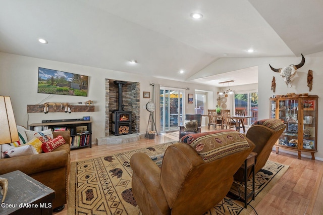 living room with light hardwood / wood-style floors, vaulted ceiling, and a wood stove