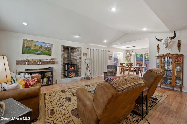 living room with vaulted ceiling, light hardwood / wood-style floors, and a wood stove