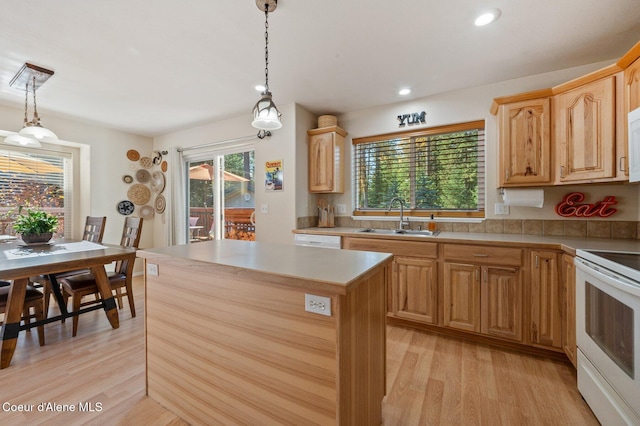 kitchen with white appliances, decorative light fixtures, sink, and a kitchen island